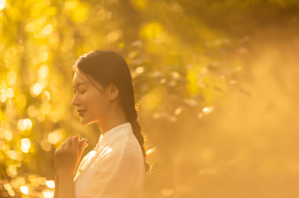 Mulher respirando em meio à natureza iluminada pelo sol